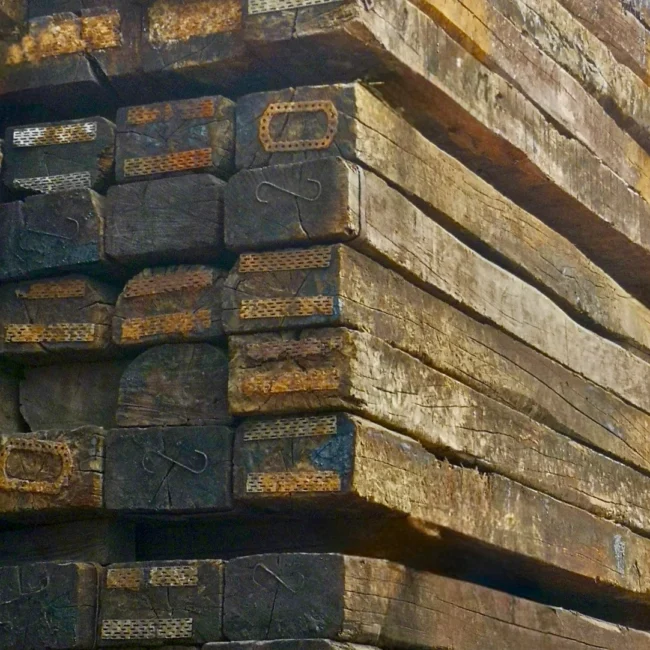 A tall stack of old reclaimed timber railway sleepers
